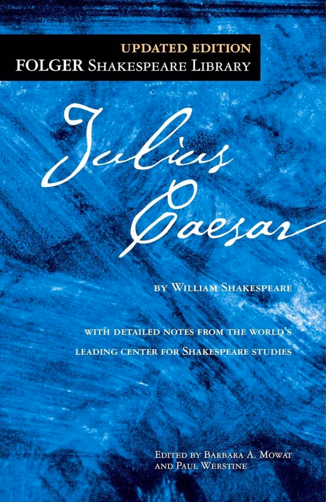 Blue textured cover for julius caesar, updated edition from the folger shakespeare library, with white cursive title and author credit.