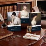 Three penguin classics editions of jane austen novels displayed on a wooden desk with reading glasses, a feather quill, and handwritten notes nearby.