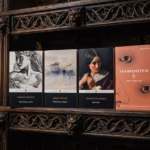 Row of classic novels on a dark carved wooden shelf, including dickens' great expectations, wuthering heights, jane eyre, and frankenstein.